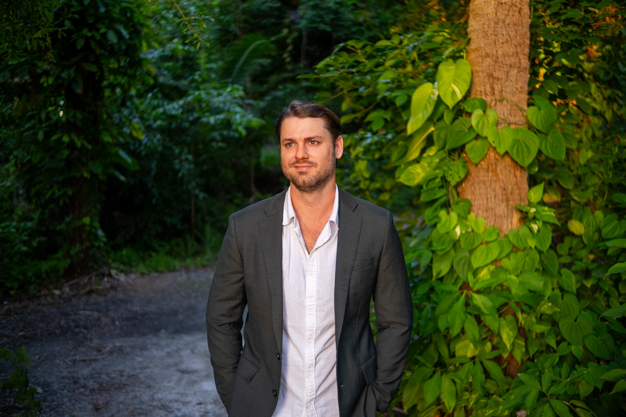 Elliot Taylor on a shaded Lee County path at golden hour, jacket over an open collar.