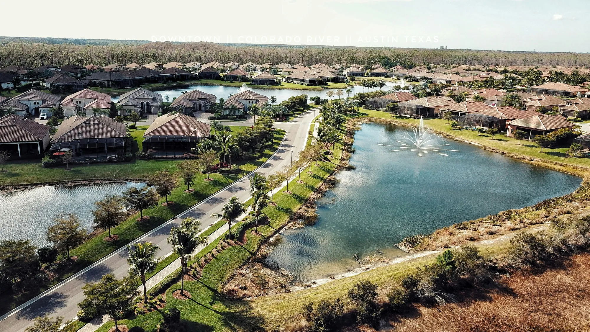 An aerial sweep of a master-planned Lee County subdivision, tile rooftops and man-made ponds pressed against the pine preserve at its edge.